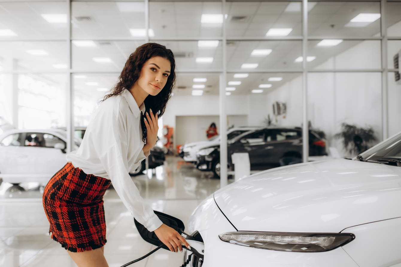 mujer cargando un coche eléctrico en un garaje con techo tensado e iliminacion led